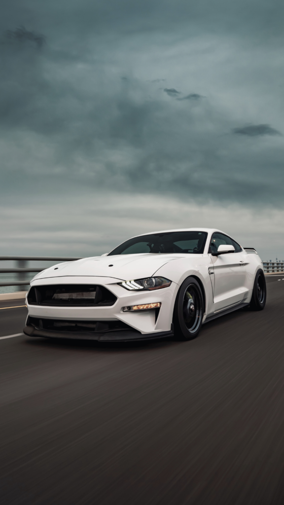 a white mustang racing in the highway