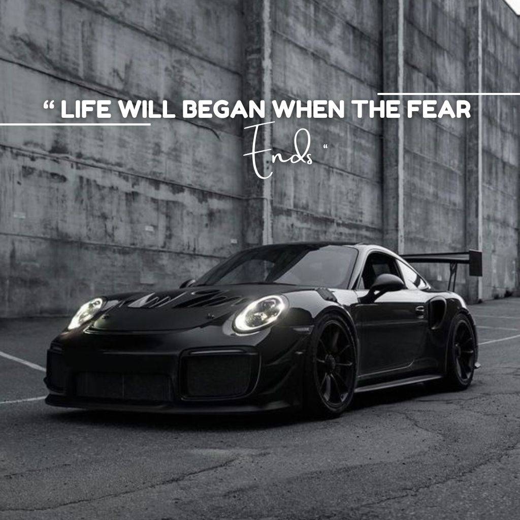 "Sleek black sports car in an industrial setting with the motivational quote 'Life will begin when the fear ends.'"